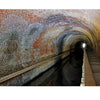 A brick-lined tunnel with a narrow walkway curves alongside a canal, illuminated by light at the end—echoing the historic journey featured in The Chesapeake and Ohio Canal by Schiffer Publishing, Ltd.