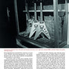 Three guitars called The Ultimate from Schiffer Publishing, Ltd. are displayed upright in a showcase, each with a sharp Flying V body shape, set against a dark background and dramatically highlighted by spotlights.