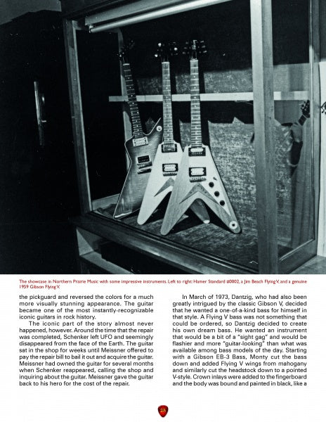 Three guitars called The Ultimate from Schiffer Publishing, Ltd. are displayed upright in a showcase, each with a sharp Flying V body shape, set against a dark background and dramatically highlighted by spotlights.