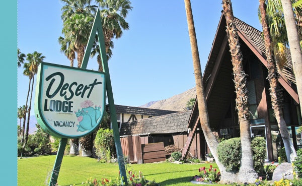 A green and white Desert Lodge Vacancy sign stands amid palm trees and mid-century modern architecture, evoking classic Palm Springs vibes. Featured in Palm Springs by Schiffer Publishing, Ltd., under a clear sky.