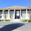 Palm Springs by Schiffer Publishing, Ltd. features a mid-century modern building with tall windows and vertical columns, evoking classic Palm Springs postcards, with mountain and palm tree views and stairs to the main entrance.