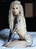 A tattooed woman with long, pale dreadlocks poses nude in profile against a dark backdrop. Showcasing striking body art, she appears as a bold Ink ’N Girls model from Schiffer Publishing, Ltd., with "ANGEL DIES" at the image’s base.