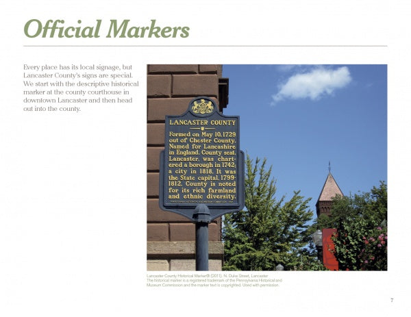 The book "Signs of Lancaster County" by Schiffer Publishing, Ltd. explores historical markers like one set near bushes before a red brick building, detailing Lancaster County's founding and its place in Amish Country.