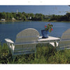 Cape Cod along the Shore" by Schiffer Publishing, Ltd. features two white Adirondack chairs and a small table with a potted plant, overlooking a tranquil lake on the Cape Cod shoreline beneath a clear blue sky.