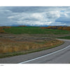Yellowstone Country by Schiffer Publishing, Ltd. showcases panoramic views of winding rural roads, grassy fields, autumn trees, and distant snow-capped peaks—capturing the stunning scenery of Yellowstone National Park.