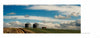 Two metal grain silos and a red farm truck on a grassy hill under dramatic clouds evoke scenes from "Yellowstone Country" by Schiffer Publishing, Ltd., with a dirt road winding through the picturesque landscape.