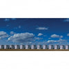 A long row of large silver grain silos stretches across flat land under a bright blue sky, evoking the sweeping vistas featured in "Yellowstone Country" by Schiffer Publishing, Ltd.