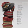 A woven fiber sculpture in black, red, and tan stands beside a contents list for "Artistry in Fiber, Vol. 2" by Schiffer Publishing, Ltd., highlighting sections and names of contemporary three-dimensional artists.