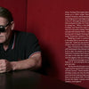 A man in a black polo shirt and sunglasses sits at a table with an 80s Redux mug. Text about Dave Wakeling, one of the iconic 1980s musicians, and his music career fills the right side on a red background. Brand: Schiffer Publishing, Ltd.