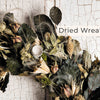 A close-up of a dried Schiffer Publishing, Ltd. Wreaths made of leaves, seed pods, and grasses, set against a white rustic background. "Wreaths" is overlaid in the upper right corner, ideal for contemporary decor lovers.
