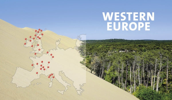 A sand dune overlays a forest, evoking adventure. On the dune, a map of Western Europe is pinned in red. Large white text reads The Great Outdoors by Schiffer Publishing, Ltd., set against a clear blue sky.