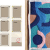 Instructional page by Schiffer Publishing, Ltd. shows how to hem fabric for beginners, with diagrams left and a vibrant punch needle textile—blue, pink, green, and peach shapes—on the right. Product: Punch Needle.