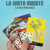 A hand with turquoise nails holds three La Santa Muerte Lenormand cards by Schiffer Publishing, Ltd. against a blue background, showing La Santa Muerte with a scythe, a table of cards, and a skeleton hand holding a clover.