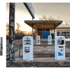 An abandoned gas station with peeling white paint, old Chevron pumps, and a rusty vintage car evokes ghost towns and the haunting beauty of America, as captured in Lost Places by Schiffer Publishing, Ltd.