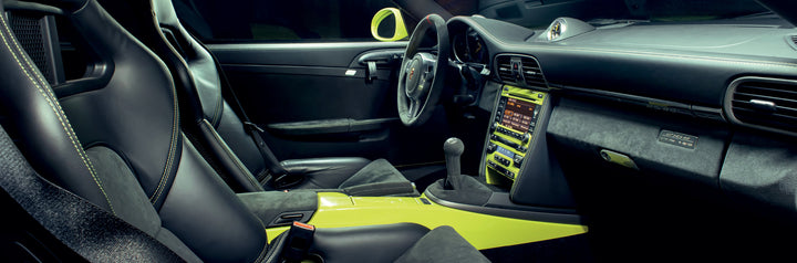 The interior featured in "Air & Water" by Schiffer Publishing, Ltd. evokes rare Porsche cars: black leather and suede seats, yellow center console, manual gear shift, and a modern dashboard with illuminated controls.