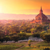 Experience the sunset glow over ancient temples in Bagan, Myanmar, as lush trees and roaming cattle create a timeless scene—discover it all in "Monumental" by Schiffer Publishing, Ltd.