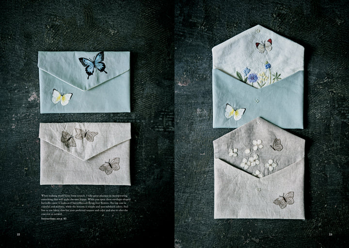 Juno's Nature Embroidery Notebook by Schiffer Publishing, Ltd. is shown on a dark surface with covers featuring delicate butterfly and flower embroidery in soft pastel and natural tones.