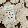 The Paint-Your-Own Holiday Decorations kit by Schiffer Publishing, Ltd. includes unpainted wooden ornaments, a paintbrush, and an instruction card, perfect for creating festive watercolor holiday décor.