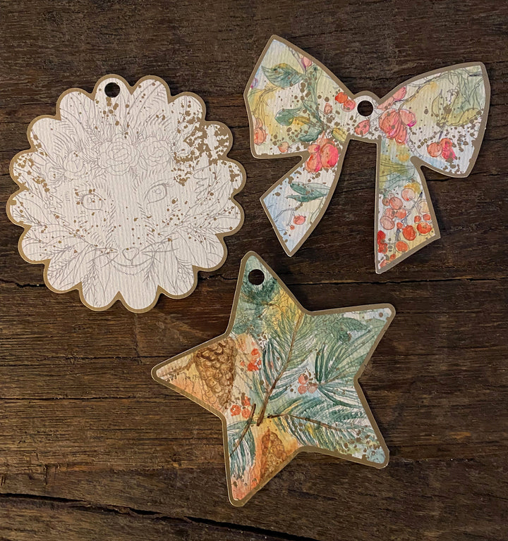 Three wooden ornaments from Schiffer Publishing’s Paint-Your-Own Holiday Decorations: a scalloped circle with an animal face, a floral-patterned bow, and a star with botanical detail, inspired by Kristy Rice’s watercolor holiday designs.