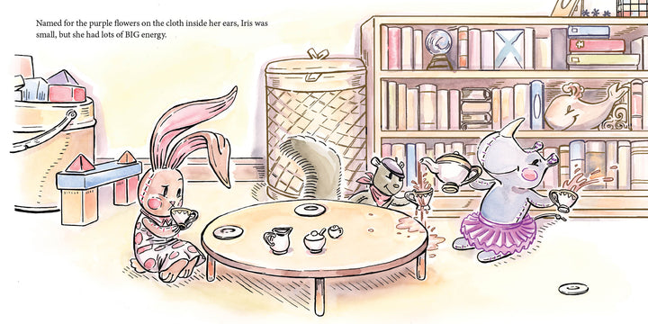 In Schiffer Publishing, Ltd.’s "Traveling Rose," three animals—a bunny in floral pajamas, a mouse, and a tutu-clad rhino—have a cozy tea party at a low table surrounded by books and toys.