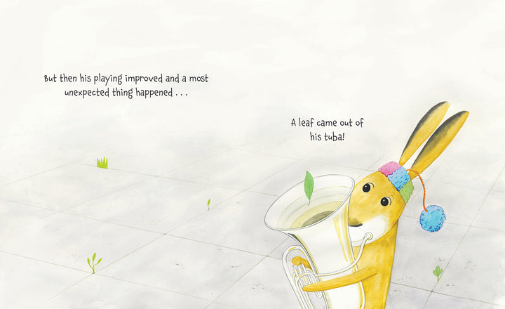 A yellow rabbit from Schiffer Publishing, Ltd.’s "The Tree in My Tuba" plays a tuba with a green leaf springing from the bell. On a light-tiled floor with grass, this children’s book scene reads: "A leaf came out of his tuba!.