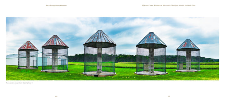 Six empty cylindrical wire grain bins with conical metal roofs stand on green grass beneath a clear sky, evoking iconic Midwest scenery as featured in Back Roads of the Midwest by Schiffer Publishing, Ltd.