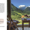 A cozy window nook overlooks an Alpine village in Slovenia—perfect for enjoying Schiffer Publishing, Ltd.'s Glamping, surrounded by forests and mountains, ideal for anyone seeking a unique European getaway.