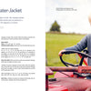 A smiling young child in a gray sweater, knitted from instructions in "Summer Knitting for Little Sweethearts" by Schiffer Publishing, Ltd., sits on a red tractor in a grassy field, holding a stuffed animal under a cloudy sky.