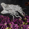 A gauzy white ghost floats over purple flowers with “Booooo!” by its mouth. A dark background and orange sign add spooky charm—perfect for Halloween parties. From Schiffer Publishing, Ltd.: How to Haunt Your House Halloween Craft Fun.