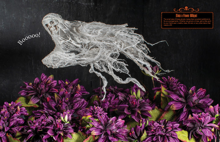 A gauzy white ghost floats over purple flowers with “Booooo!” by its mouth. A dark background and orange sign add spooky charm—perfect for Halloween parties. From Schiffer Publishing, Ltd.: How to Haunt Your House Halloween Craft Fun.