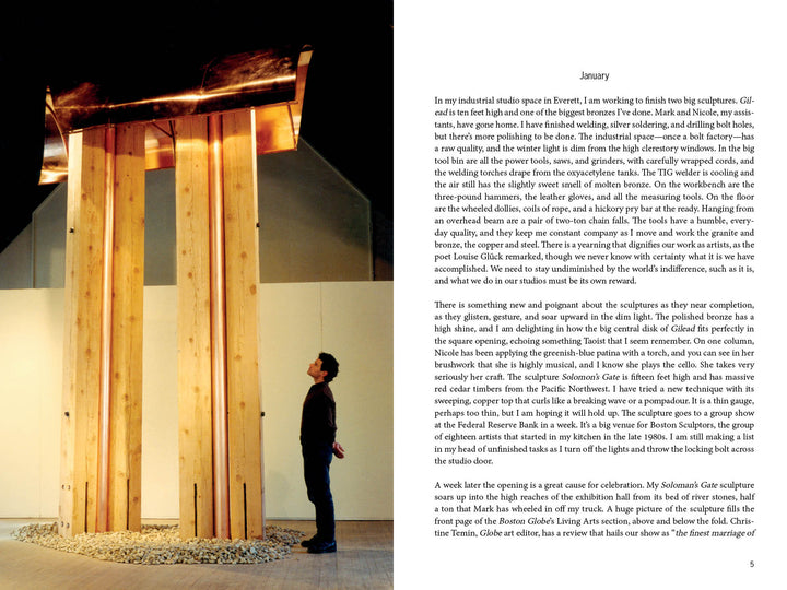 A man stands beneath "Hammer and Tongs" by Schiffer Publishing, Ltd., its vertical beams and rusted metal plate displayed on round stones in an art gallery—a striking example of public sculpture.